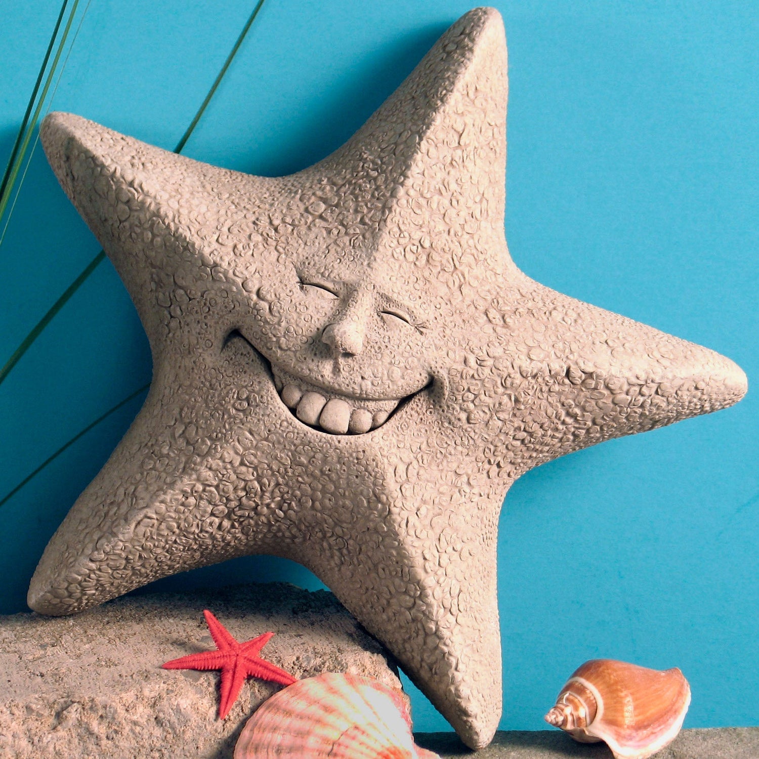 Handcrafted stone starfish sculpture with a smiling face displayed with seashells by Carruth Studio