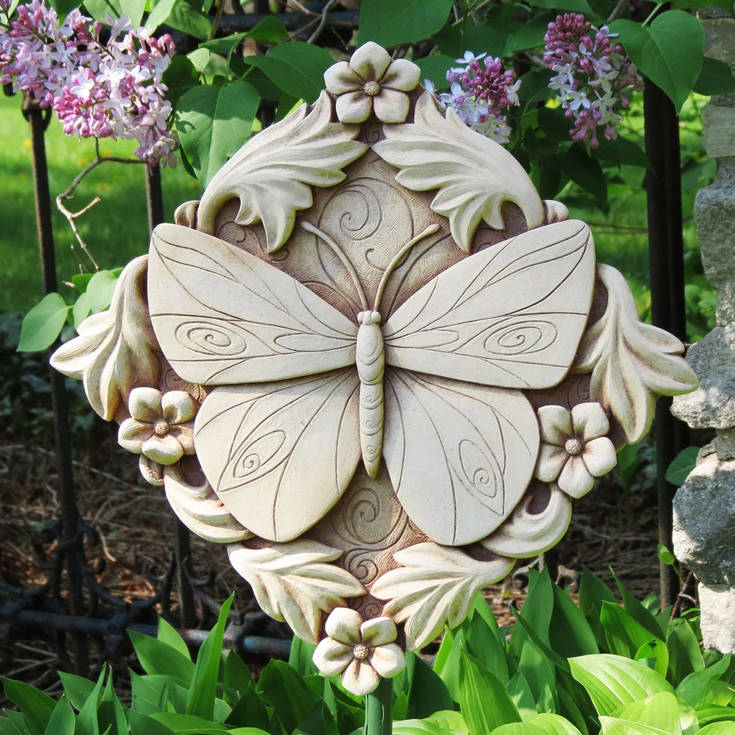Handcrafted stone butterfly sculpture with floral accents displayed in a garden by Carruth Studio