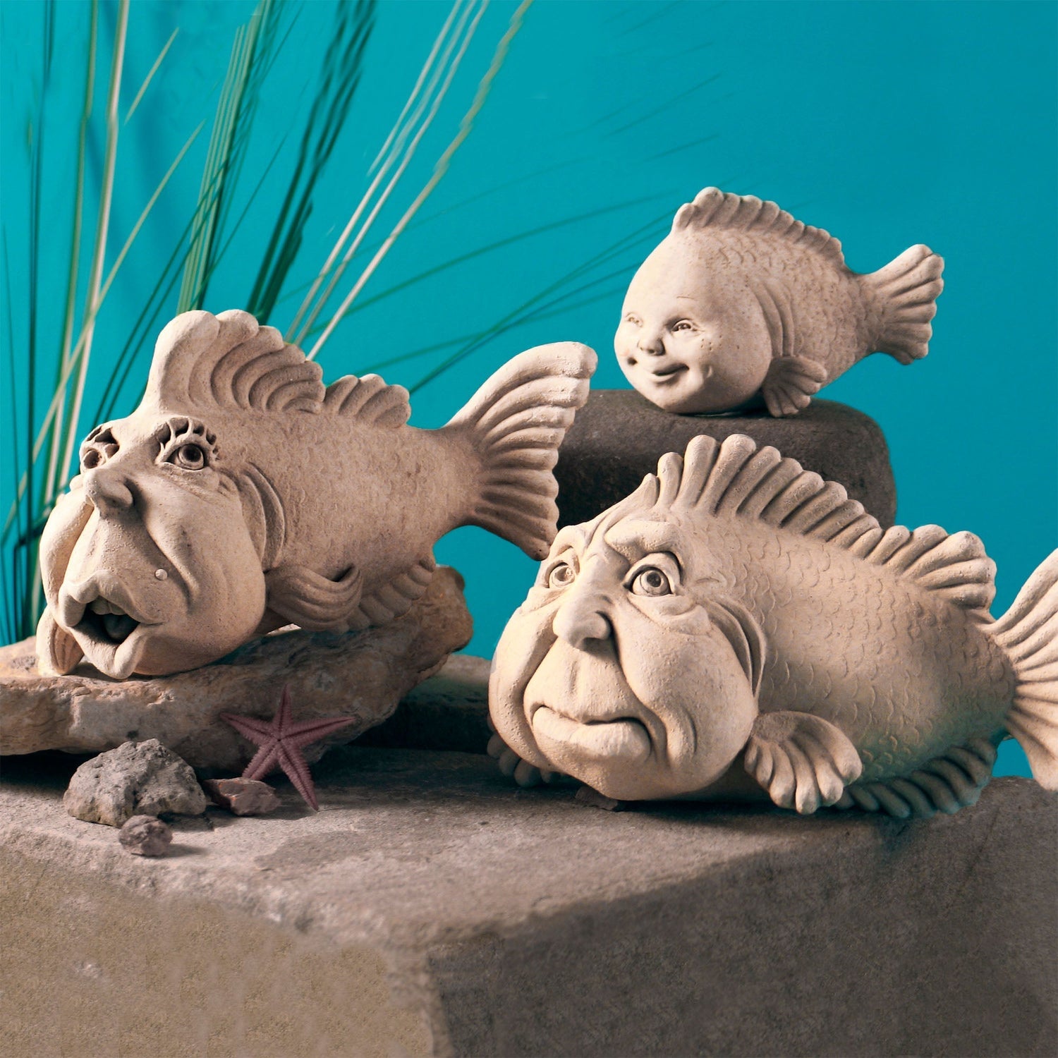 Handcrafted stone fish sculptures with whimsical faces displayed together by Carruth Studio