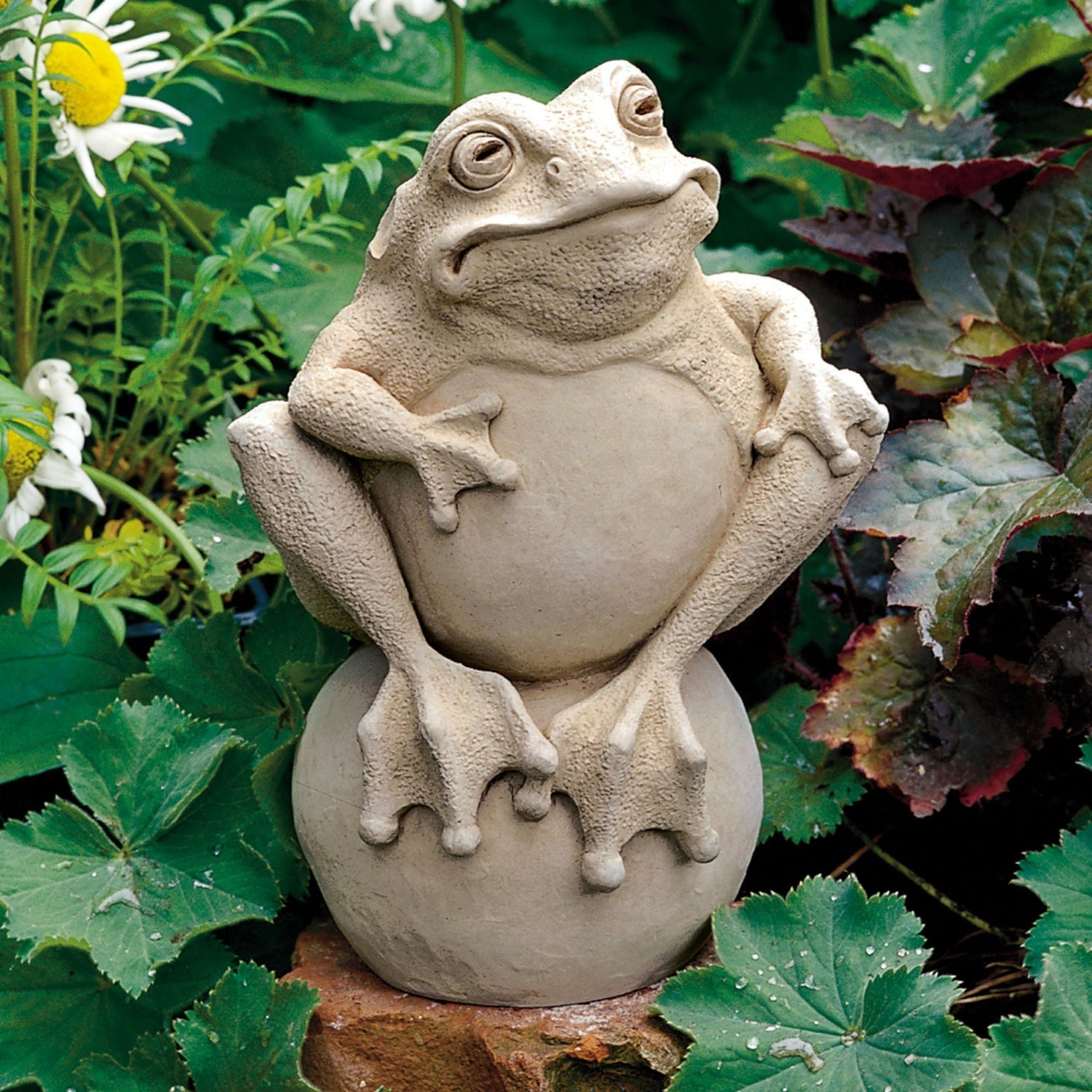 Handcrafted stone frog sculpture sitting on a garden stone by Carruth Studio